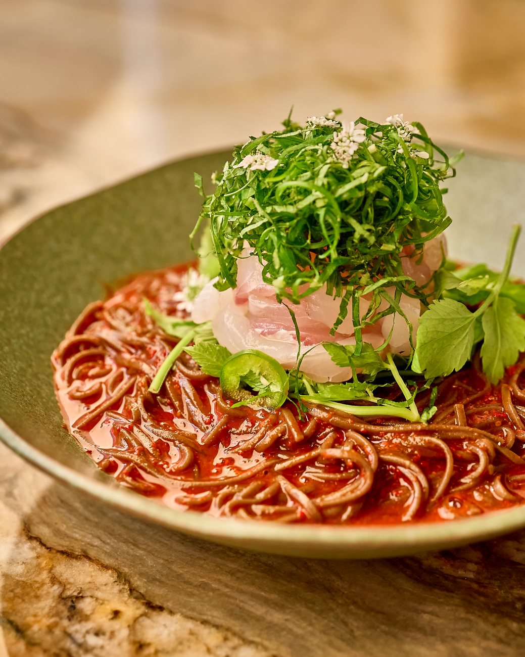 Spicy sashimi noodle: buckwheat noodles in chili sauce with sliced sea bream and perilla